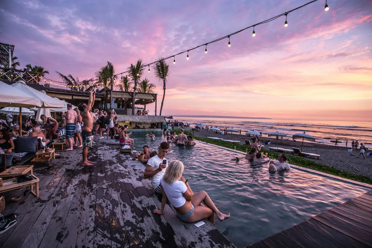 Crowd at a beach club pool in Bali at sunset
